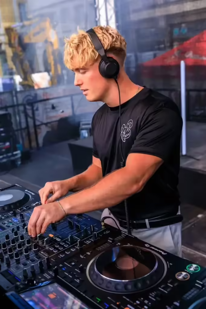 Person wearing headphones DJing at an outdoor music event.