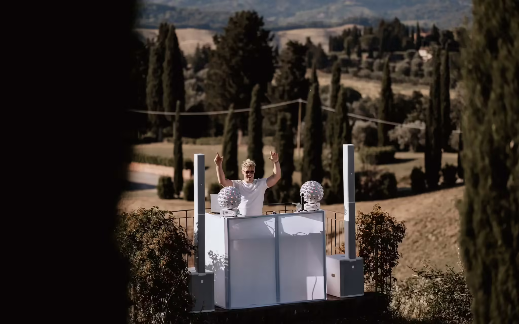 DJ Nathan White auf weißem Hochzeits-Setup in Castellare di Tonda mit toskanischer Zypressenlandschaft im Hintergrund